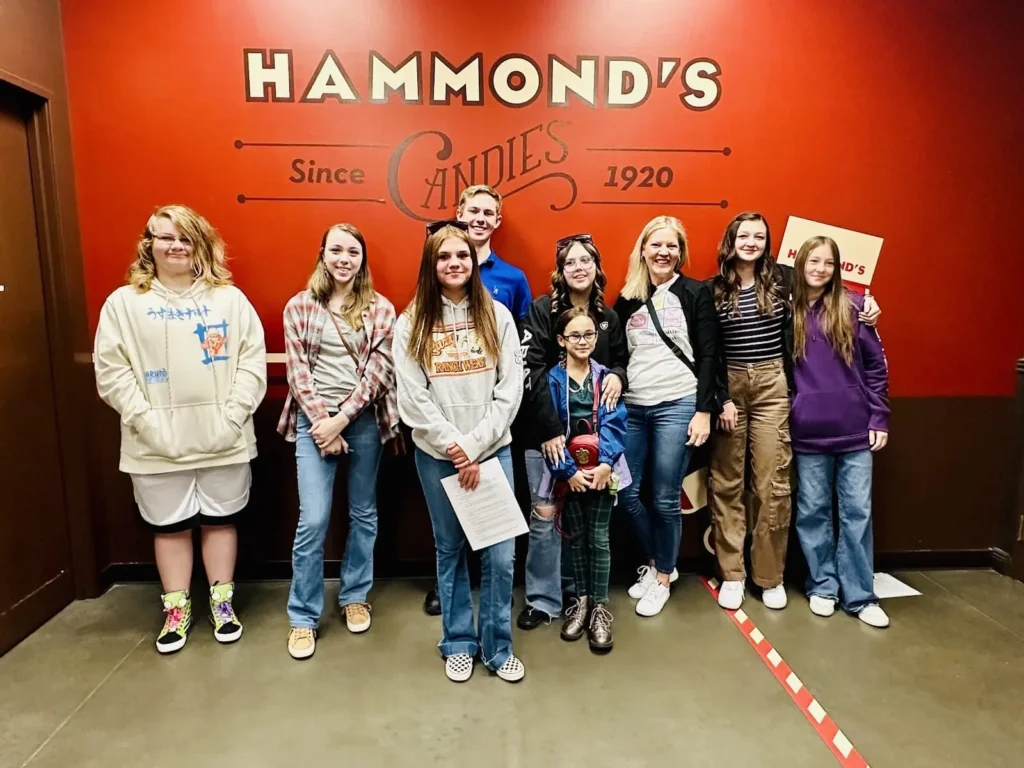 Grupo de personas posando delante del cartel de Hammond's Candies, fundada en 1920.