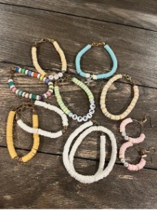 Piezas de joyería con abalorios de colores variados, incluyendo pulseras y pendientes, dispuestas sobre una superficie de madera.