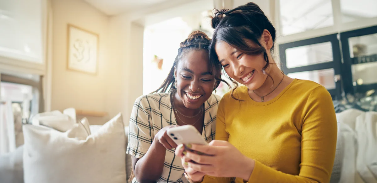 Dos estudiantes sonriendo a su teléfono