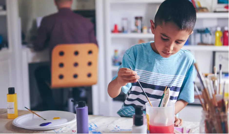 Estudiante de primaria pintando en casa